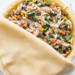 A pie filled with chicken and vegetables on a white plate.