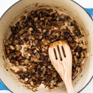 Mushrooms in a pan with a wooden spoon.