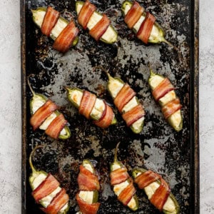 Bacon wrapped jalapenos on a baking sheet.