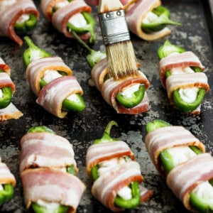 Bacon wrapped jalapenos on a baking sheet.