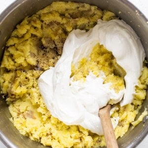 A bowl of batter with whipped cream and a wooden spoon.