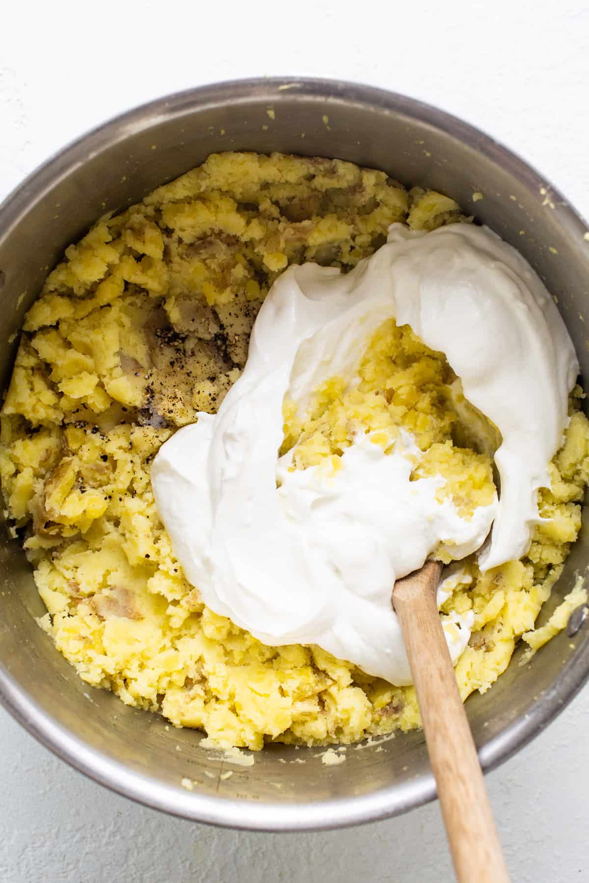 A bowl of batter with whipped cream and a wooden spoon.