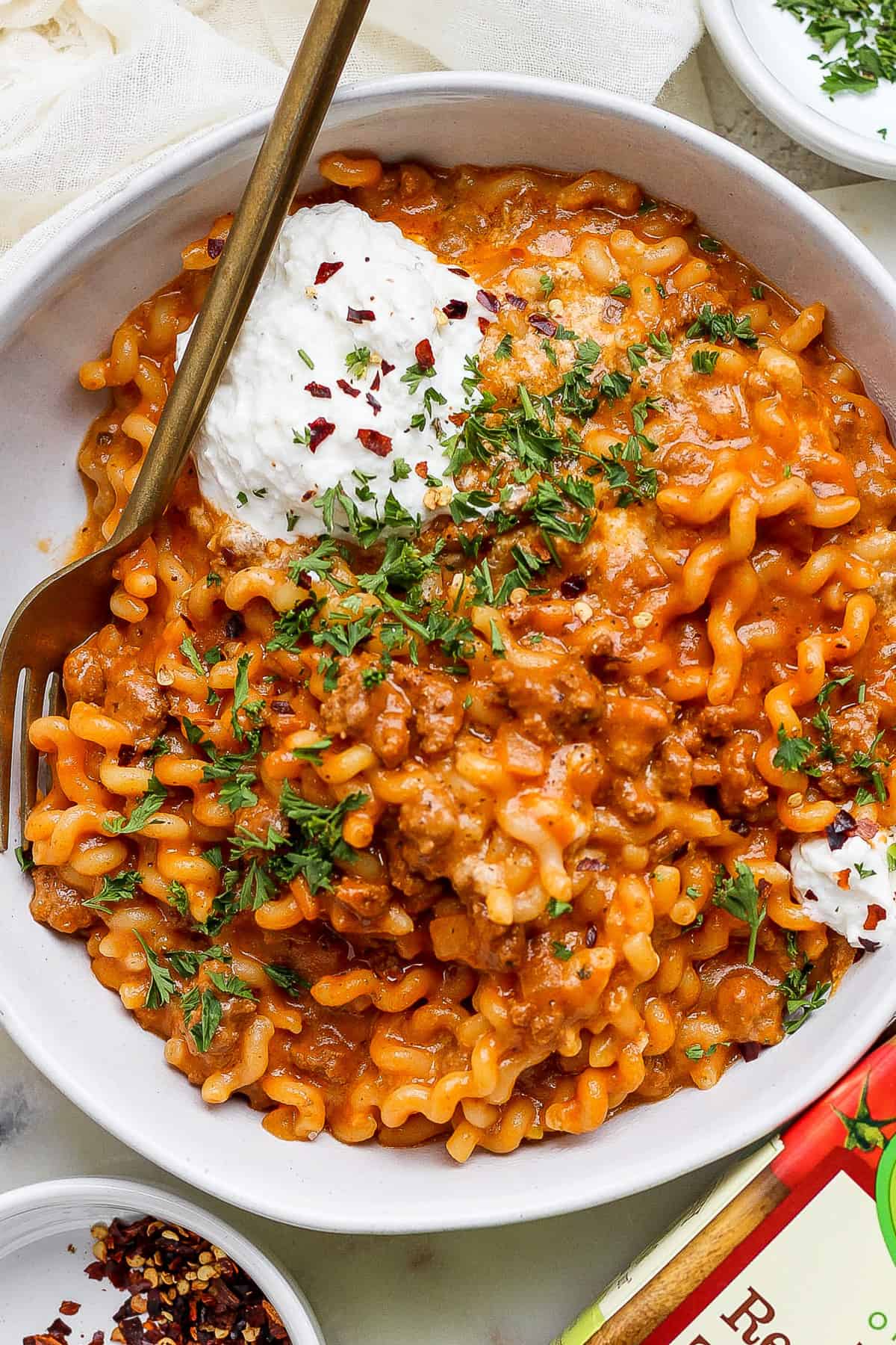 A bowl of pasta with meat sauce and sour cream.