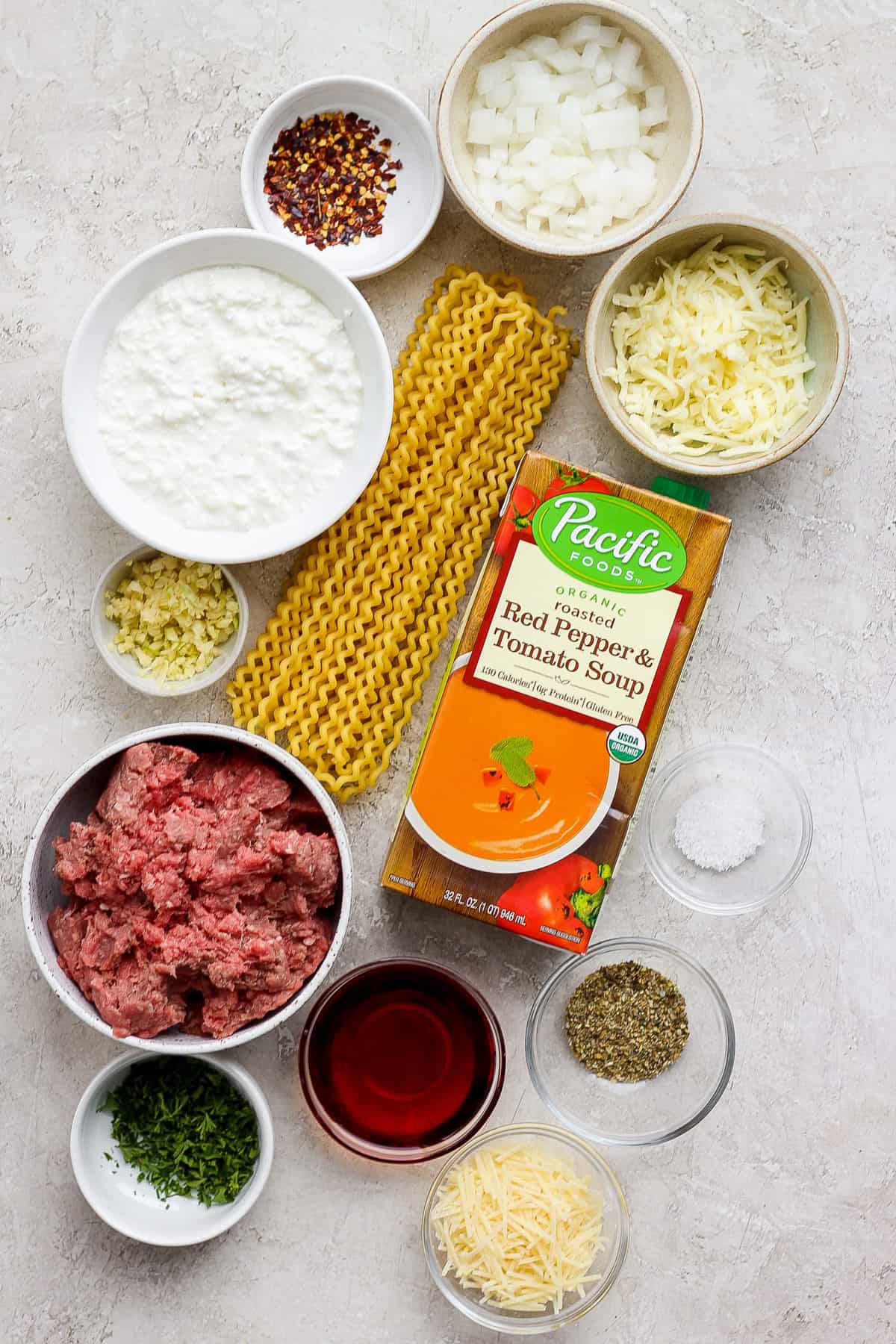 The ingredients for a pasta dish are laid out on a table.