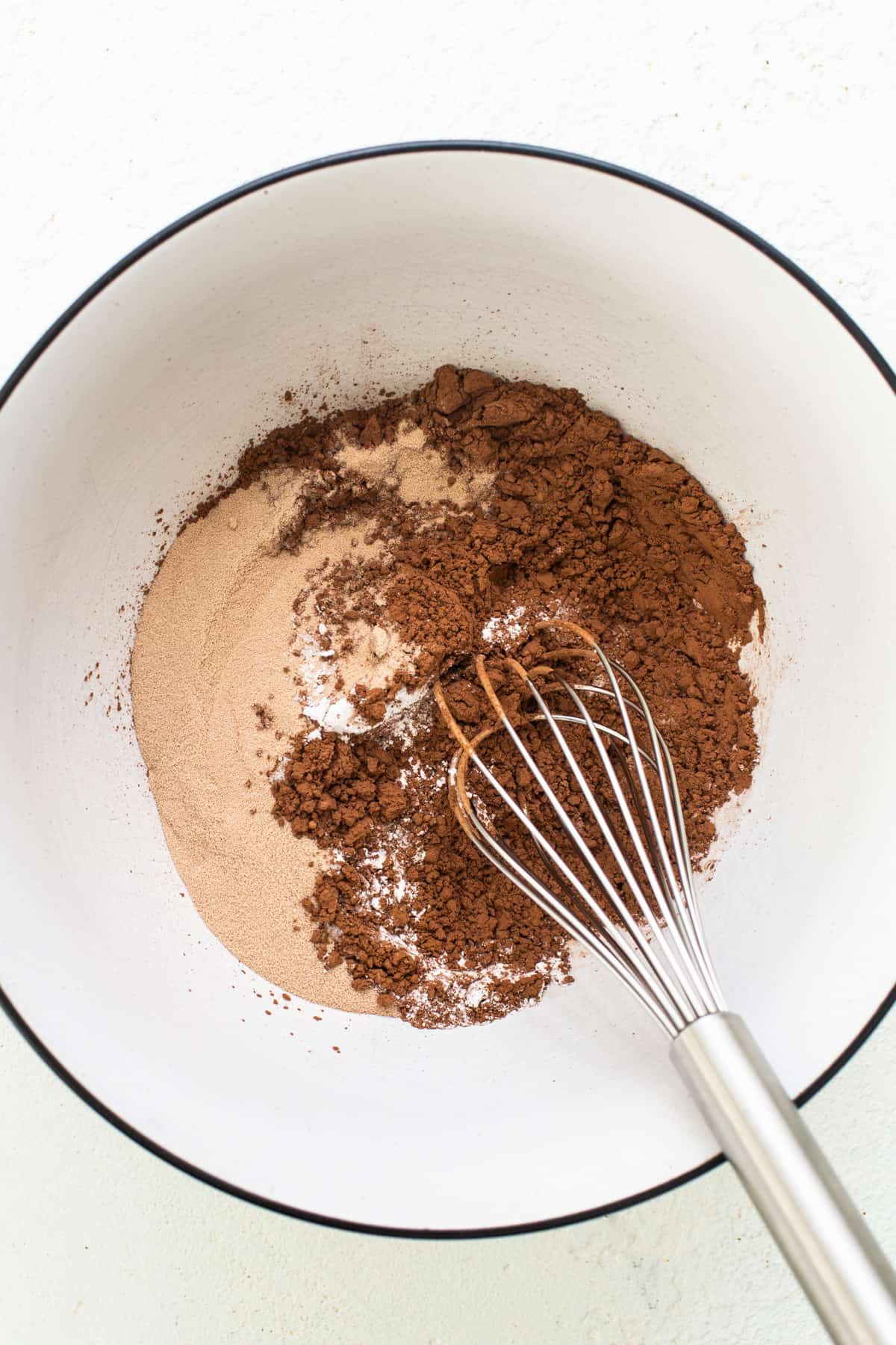 A bowl with cocoa powder and a whisk.