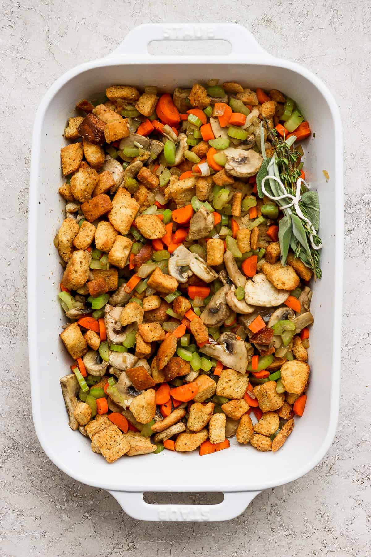 A white baking dish filled with stuffing and vegetables.