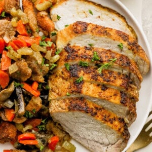 A plate of roasted chicken and vegetables on a white plate.