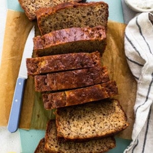 Sliced banana bread on a cutting board with a knife.