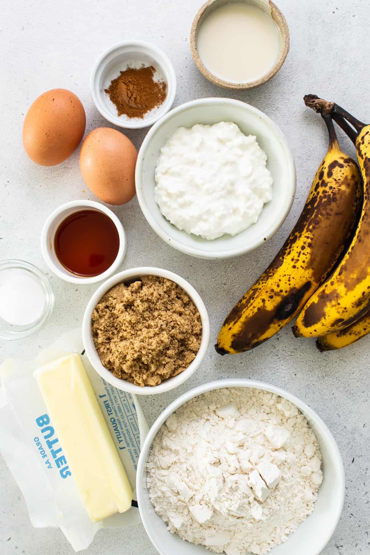 Ingredients for banana bread including bananas, flour, eggs and butter.