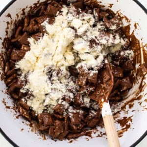 A bowl filled with chocolate and a wooden spoon.