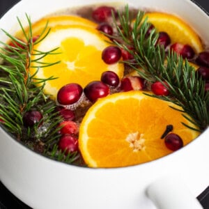 A pot with oranges, cranberries and sprigs of fir.