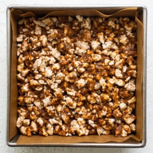 Caramel popcorn in a pan on a white surface.