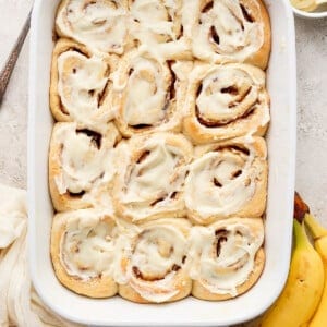 Cinnamon rolls in a baking dish with bananas.