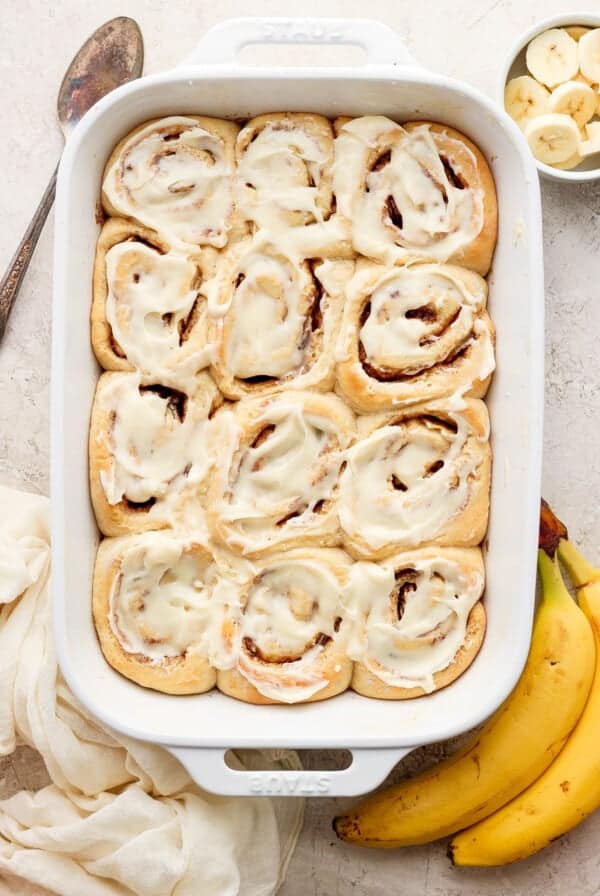 Cinnamon rolls in a baking dish with bananas.