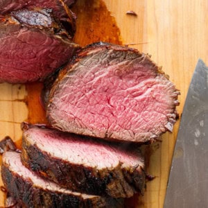 Sliced beef on a cutting board with a knife.