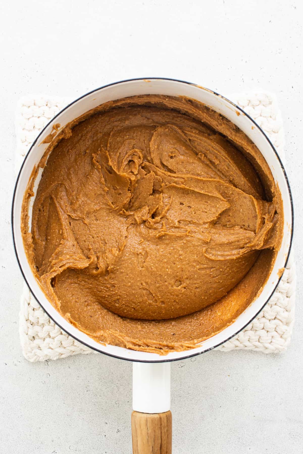 Pumpkin butter in a pan with a wooden spoon.