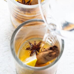 A glass of water with lemon and star anise in it.