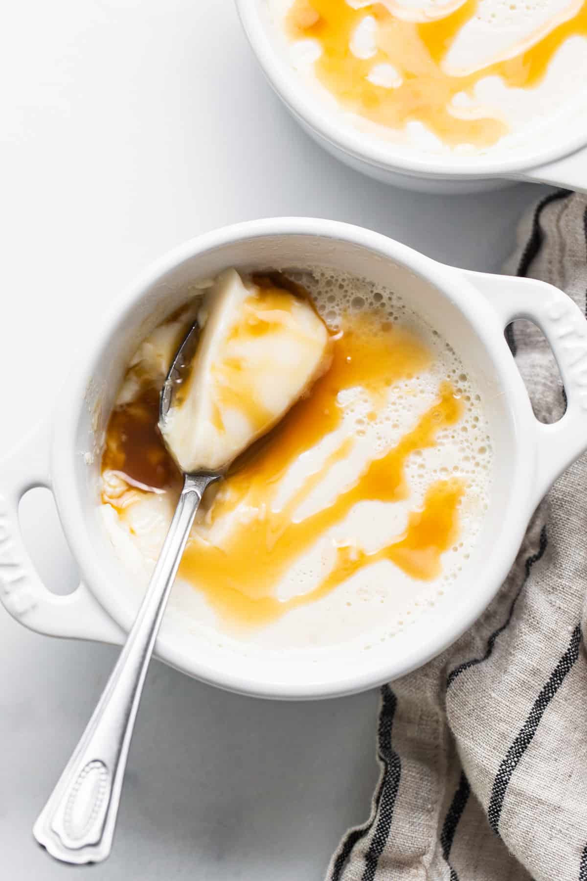 A bowl of oatmeal with caramel sauce and a spoon.