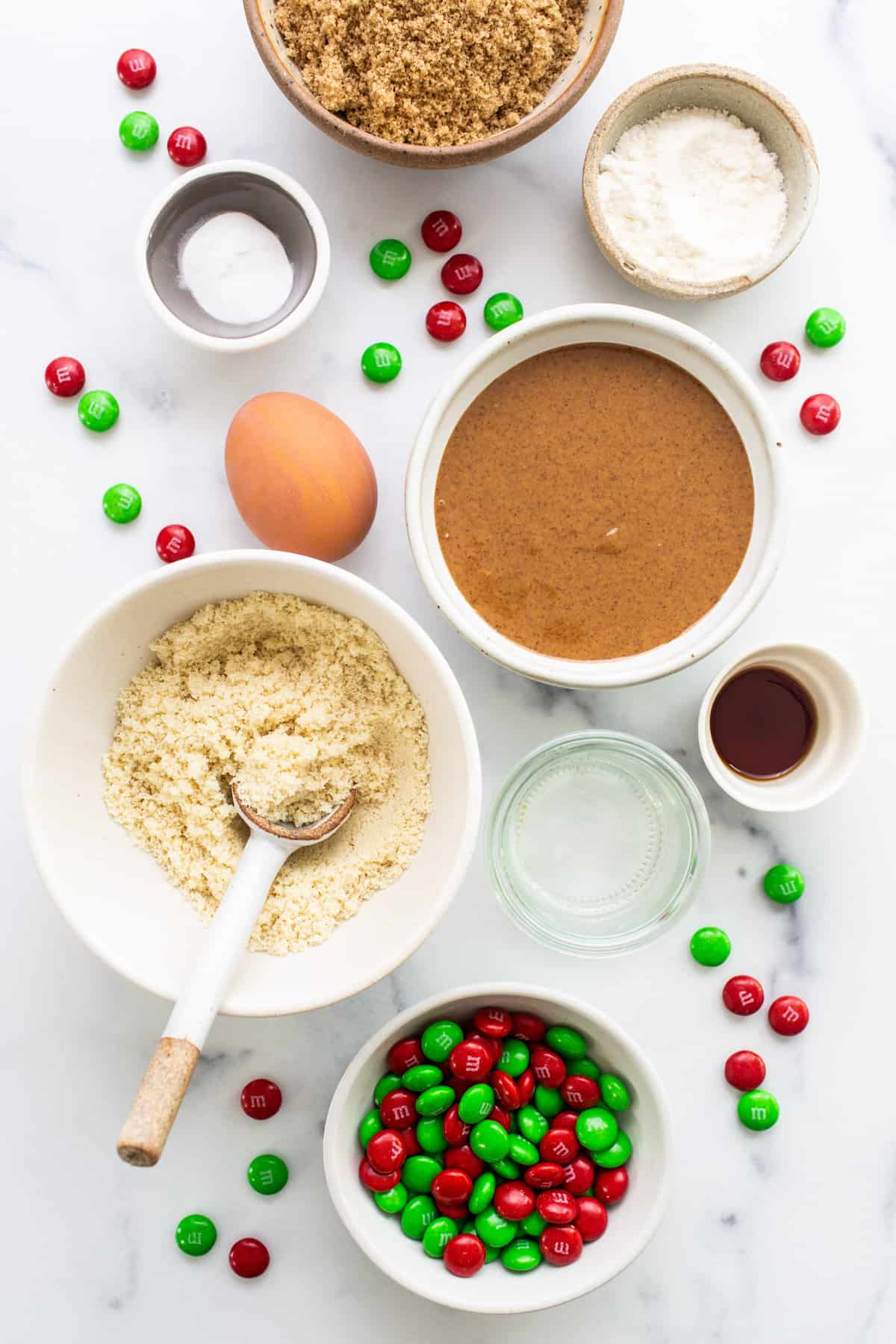 Christmas cookie ingredients on a white marble table.