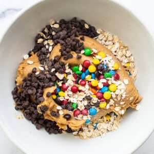 A white bowl filled with granola, oats and chocolate chips.