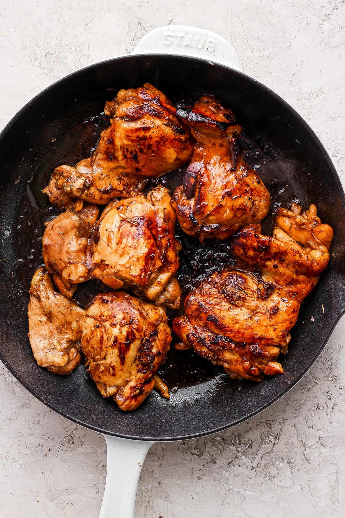 Grilled chicken in a skillet on a white background.