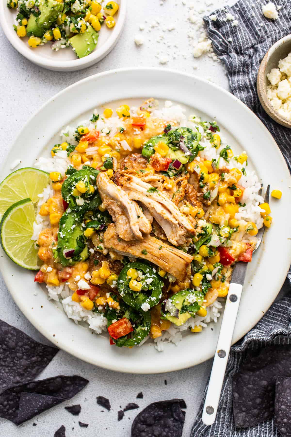 A white plate with chicken, corn and vegetables on it.