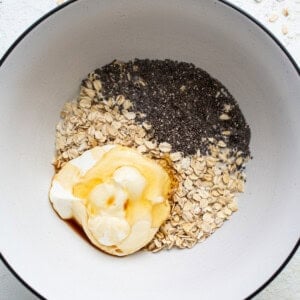 A bowl of oatmeal, oats and a dollop of whipped cream.