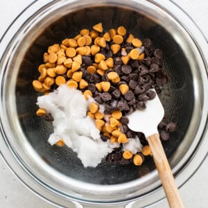 Chocolate chips in a bowl with a wooden spoon.