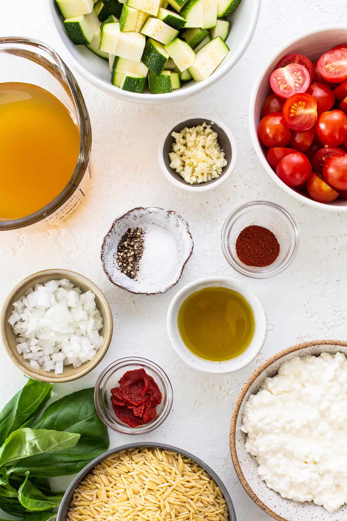 Ingredients for a pasta dish including tomatoes, zucchini, and basil.