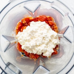 A blender filled with tomatoes and feta cheese.