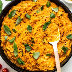 A skillet filled with mashed potatoes, tomatoes and herbs.