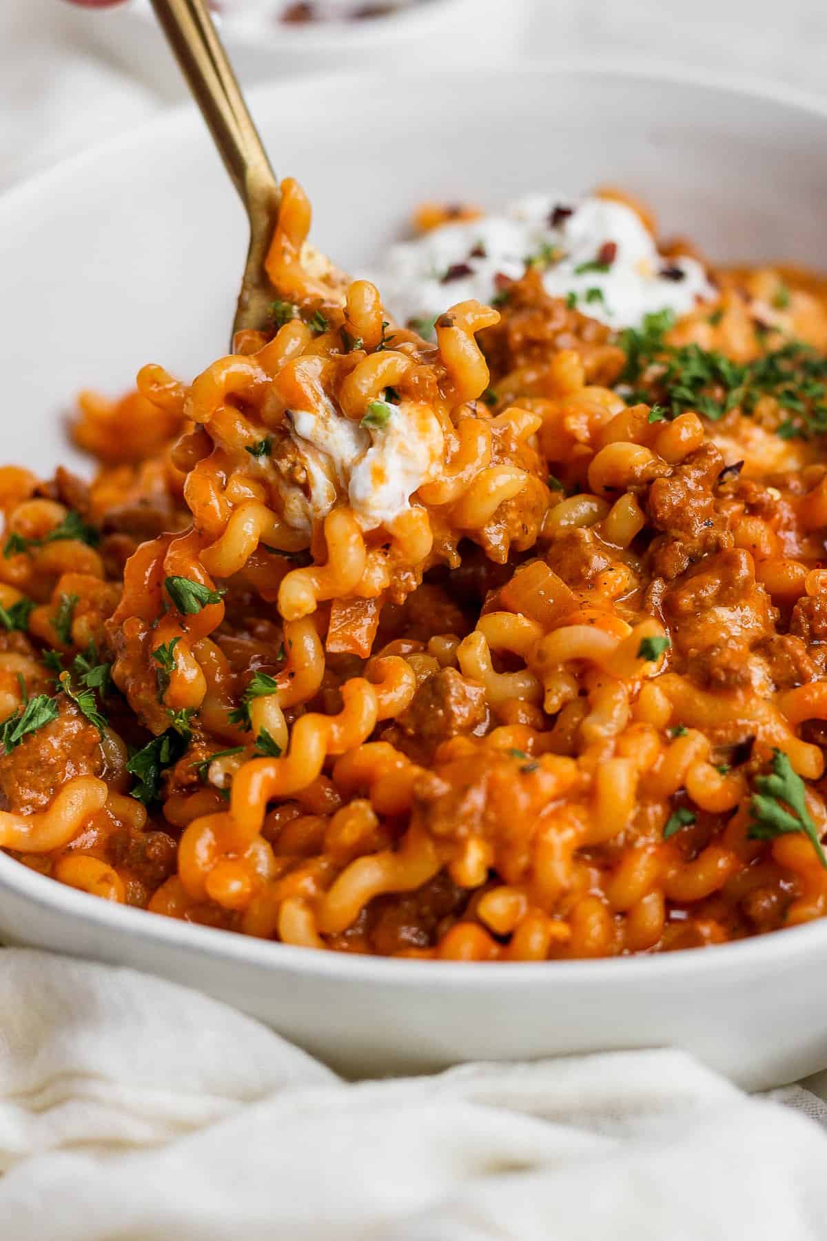 A bowl of pasta with meat sauce and sour cream.