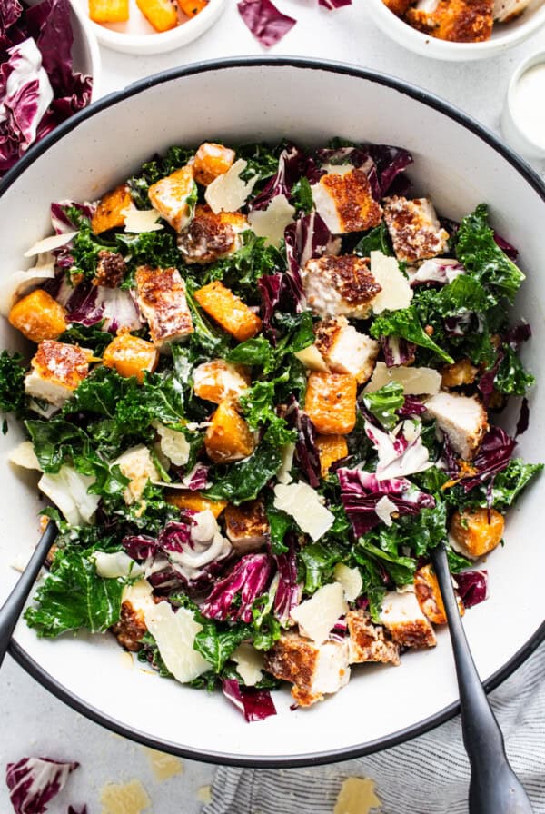 A bowl of kale salad with chicken and parmesan.