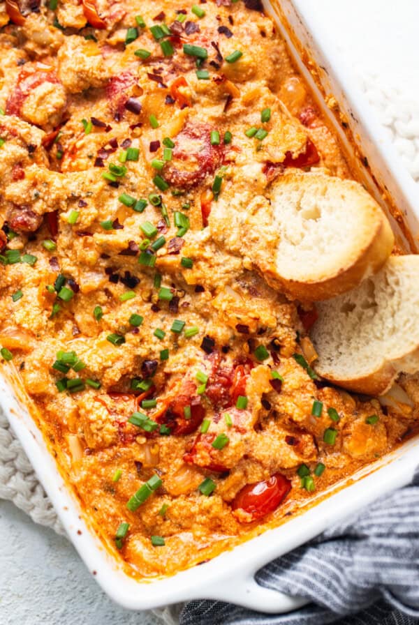 A casserole dish with chicken, tomatoes and bread.