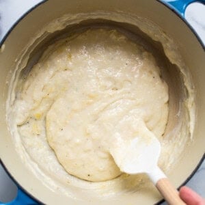 A person stirring the batter in a pot.