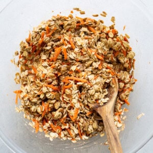 Oats in a bowl with a wooden spoon.