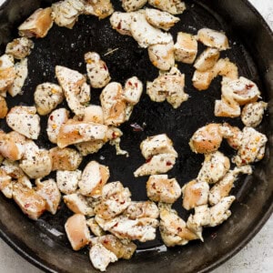 Fried chicken in a skillet on a white surface.