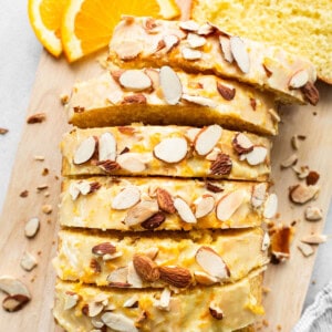 A slice of bread with almonds on a cutting board.