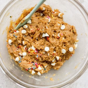 A bowl of cookie dough with sprinkles and a spoon.