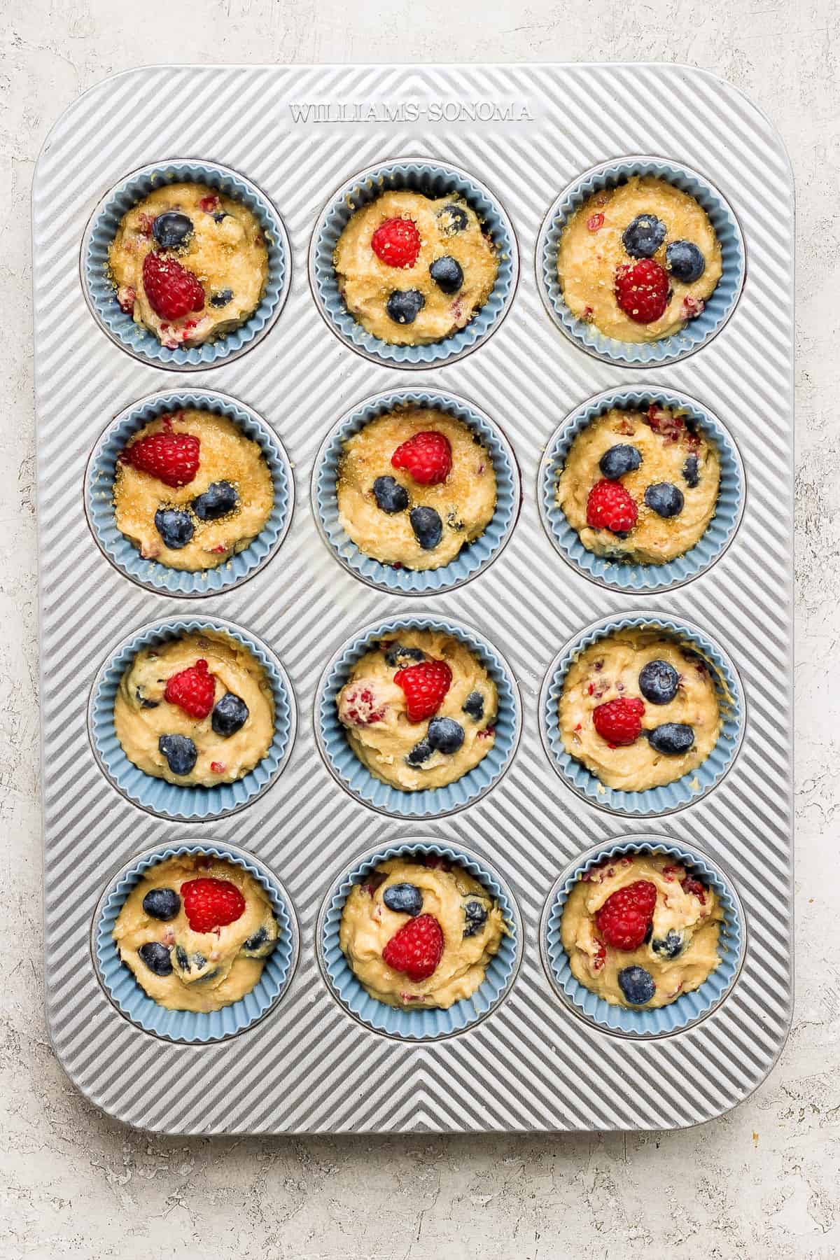 A muffin tin filled with muffins and berries.