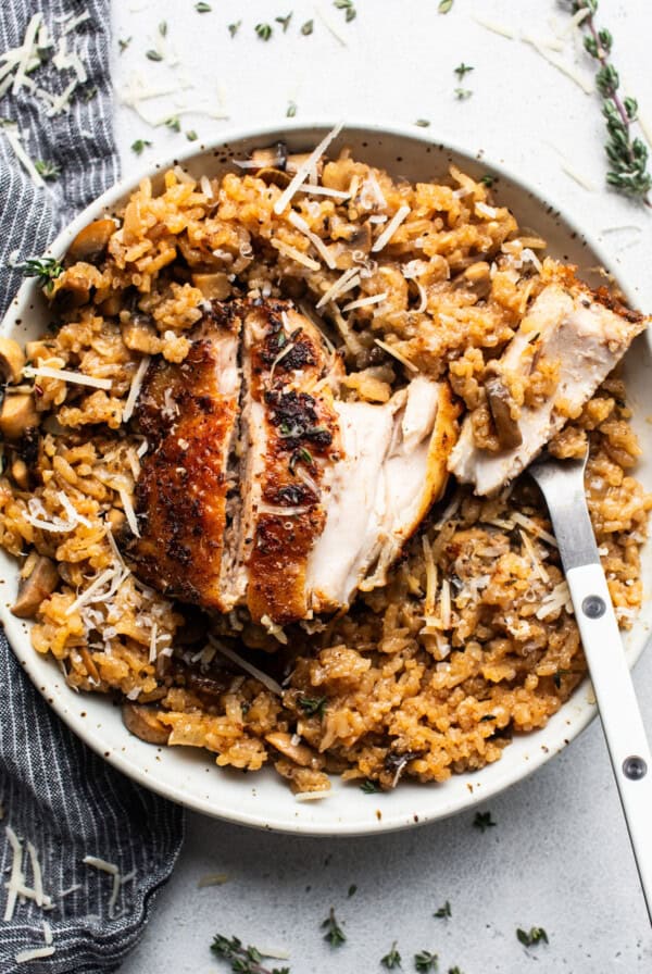 Chicken risotto with mushrooms and thyme on a plate.