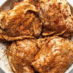 Seasoned chicken breasts in a white plate.