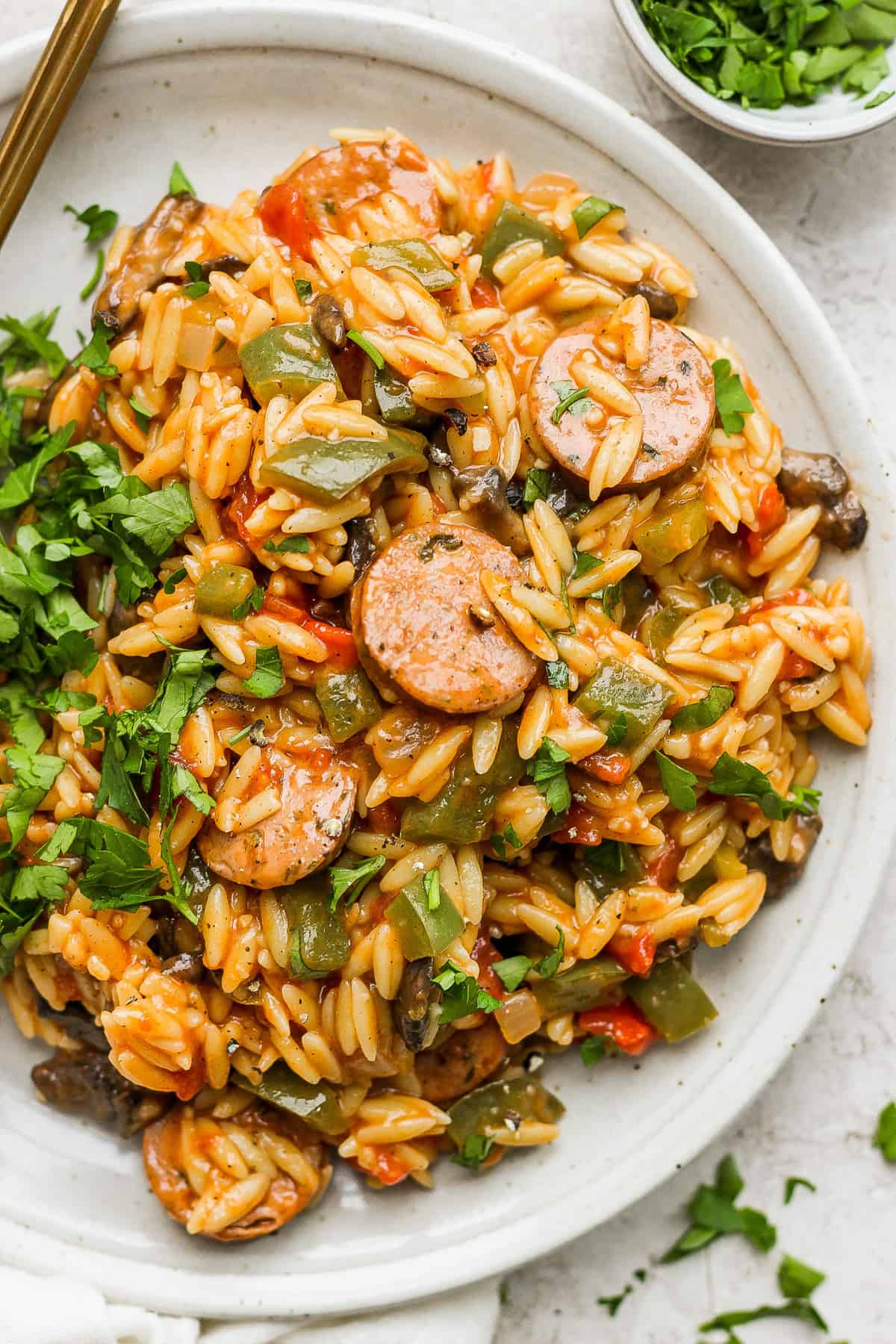 A plate of sauteed rice with sausage and vegetables.