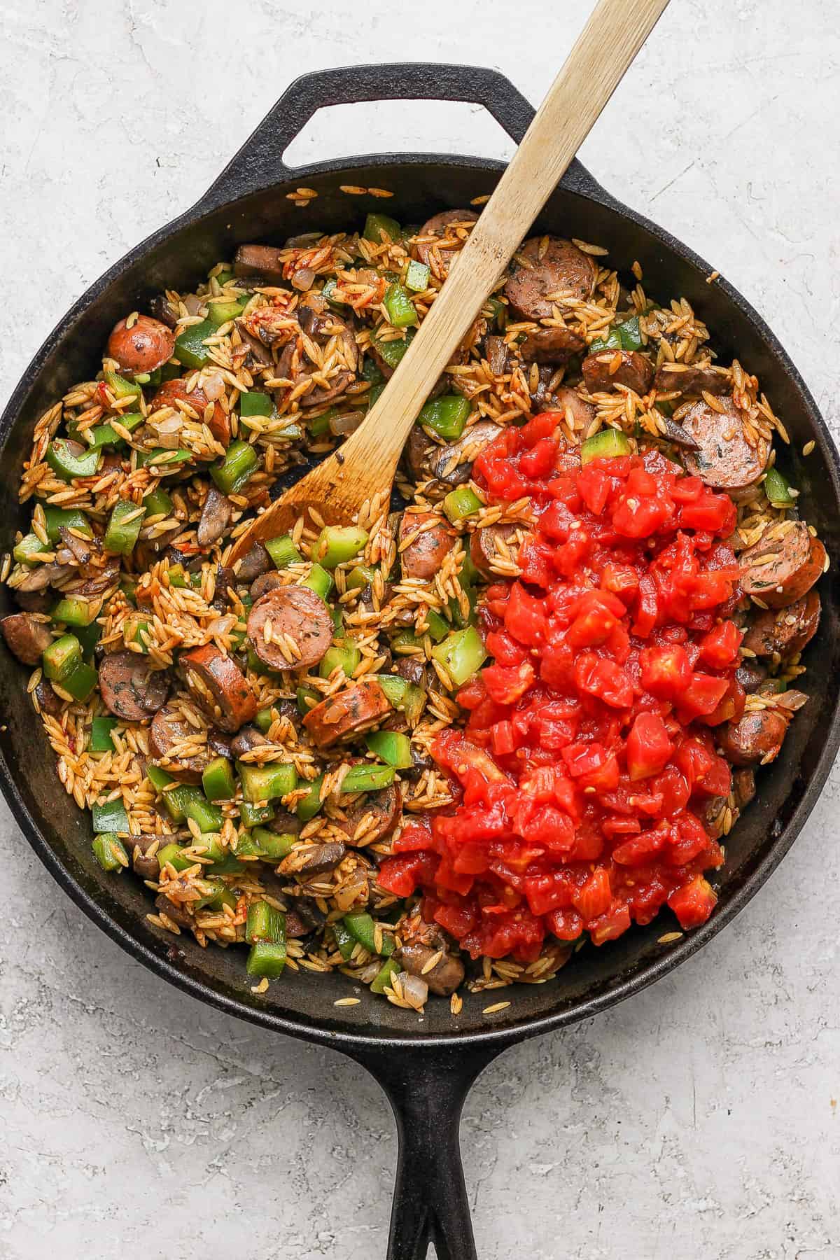 A skillet full of rice and meat with a wooden spoon.