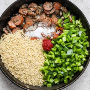 A frying pan with rice, mushrooms and green peppers.