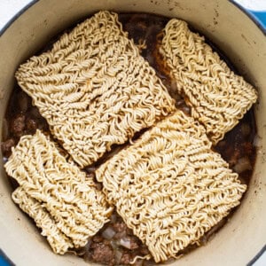 Ramen noodles in a pot on a white surface.