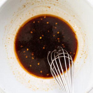 A bowl with brown liquid and a whisk.