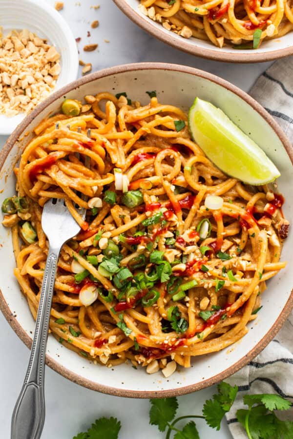 Thai peanut noodles in a bowl with a fork.