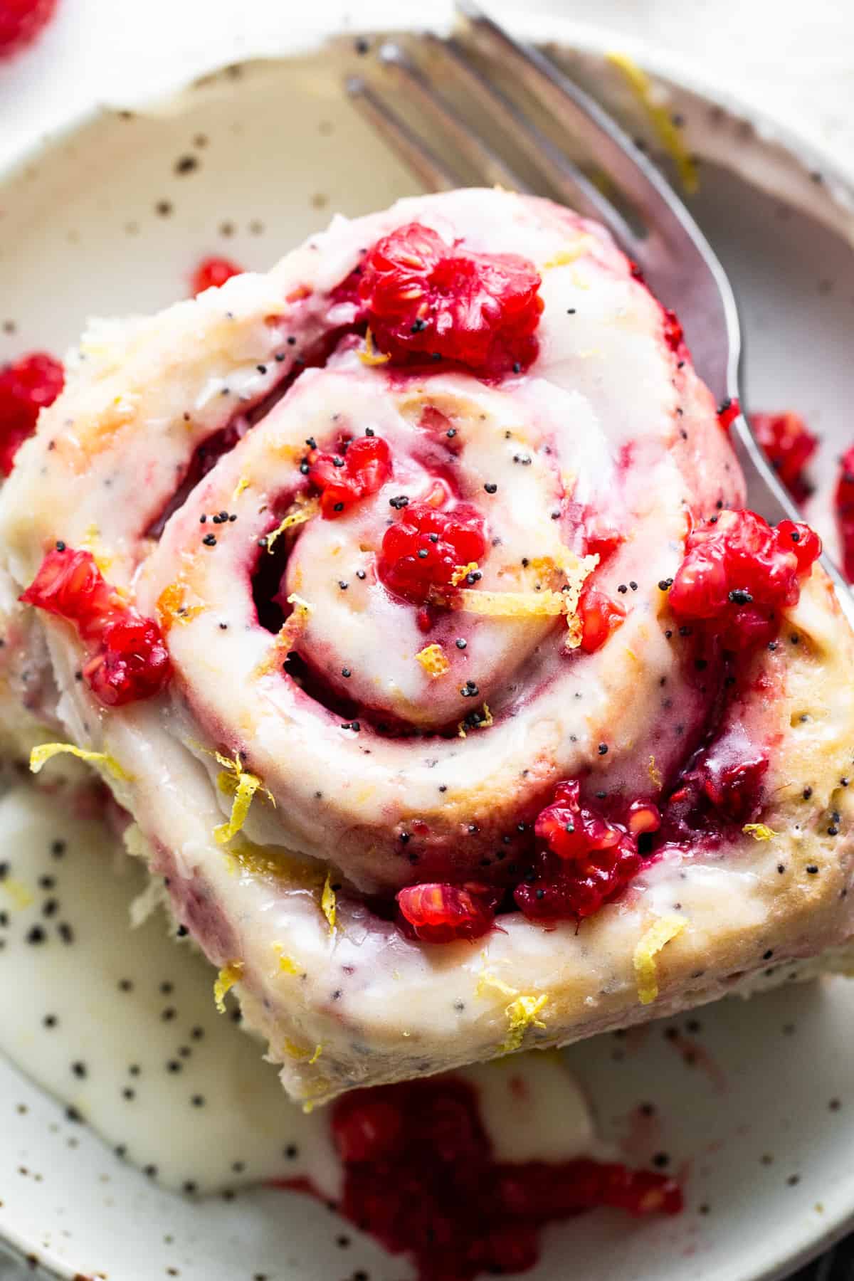 A slice of raspberry roll with a fork on a plate.