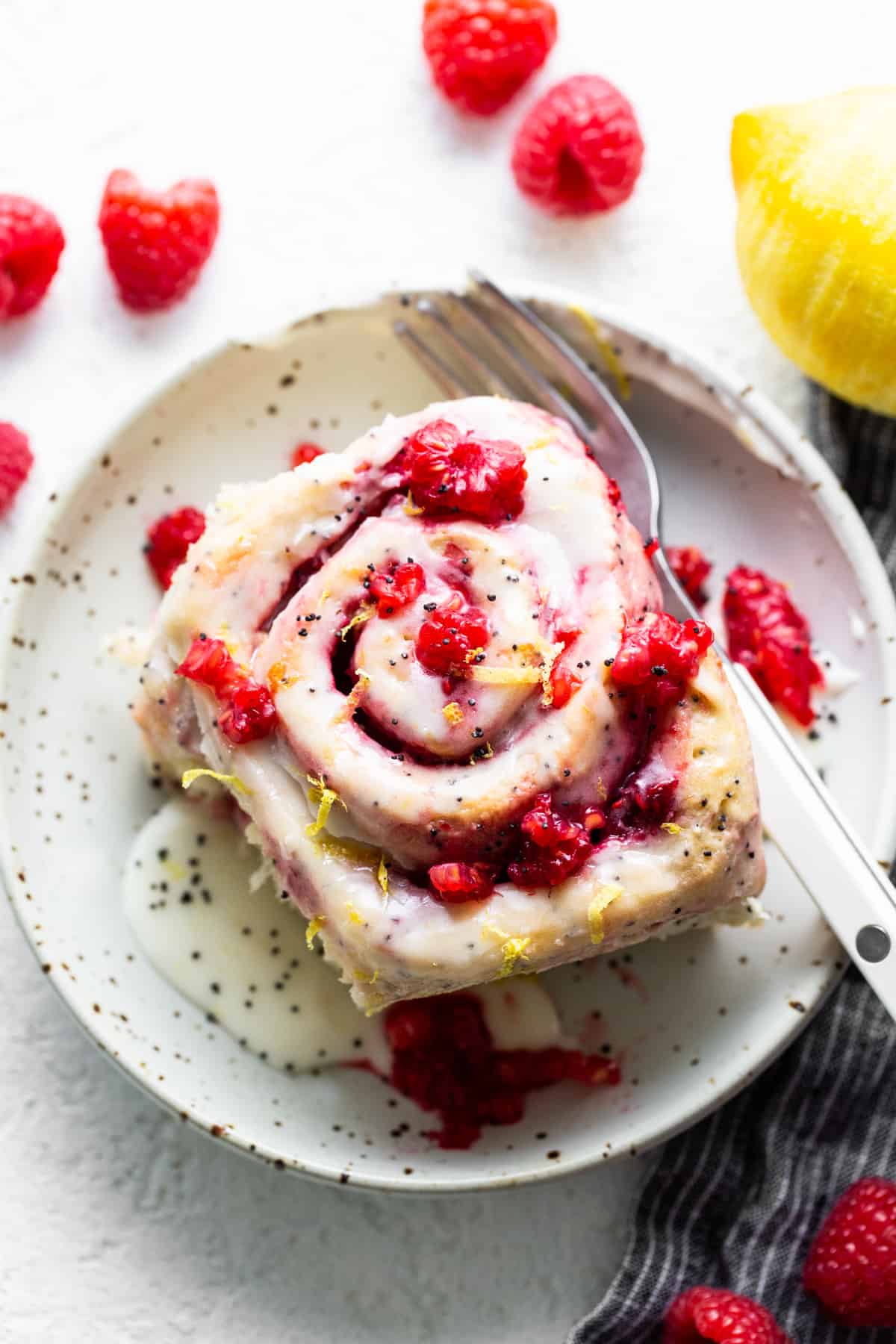 A plate with a raspberry roll and a fork.